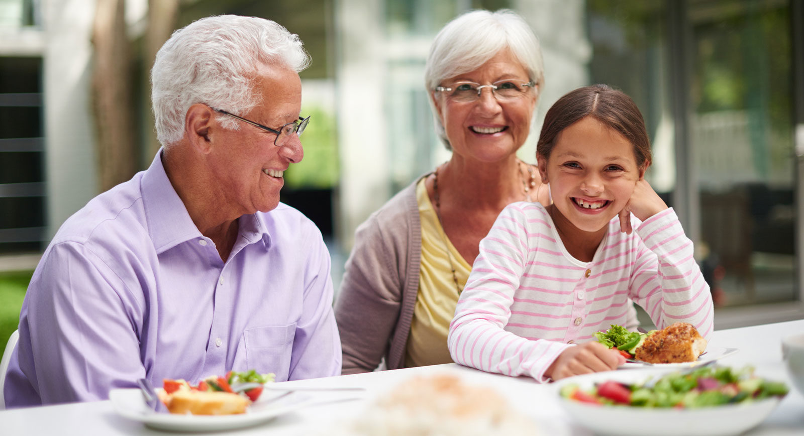 Grandparents eating with grand daughter